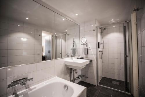 uma casa de banho com uma banheira, um lavatório e um chuveiro em Scandic Skärholmen em Estocolmo