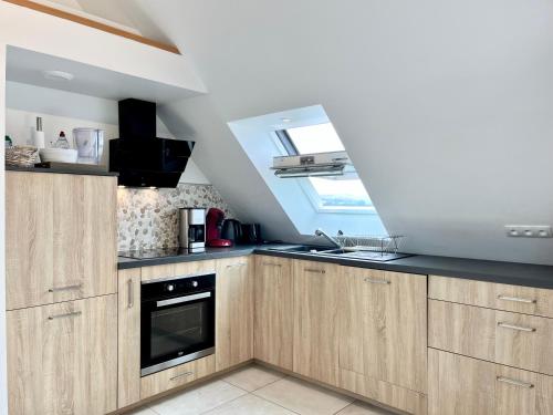 a kitchen with wooden cabinets and a window at COC - Les Sables Blancs in Wissant