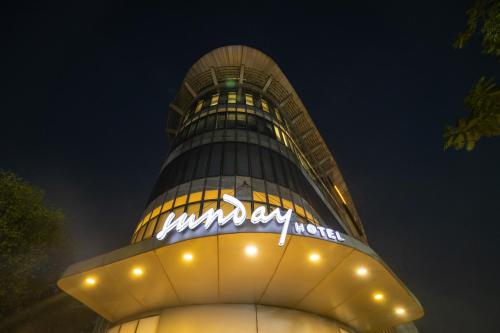 a tall building with a sign on it at night at Sunday Hotel Jaipur in Jaipur