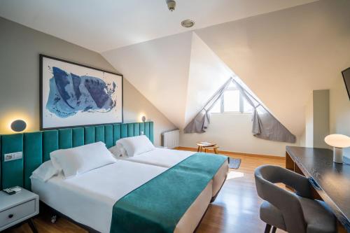 a bedroom with a large bed with a green headboard at Abba Comillas Hotel in Comillas
