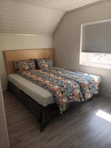 a bedroom with a bed with a colorful bedspread and a window at Olgas apartment in Tromsø