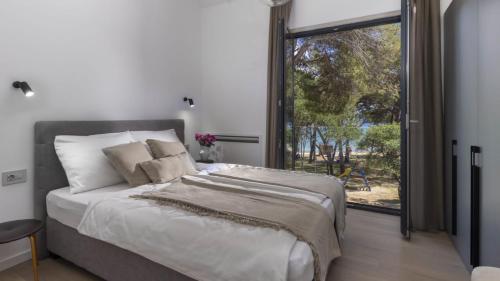 a bedroom with a large bed and a large window at Mare Solis Pinea in Mali Lošinj
