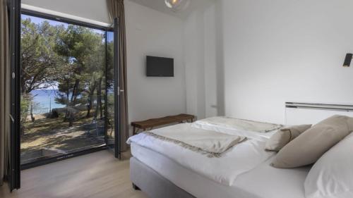 a bedroom with a bed and a large window at Mare Solis Pinea in Mali Lošinj