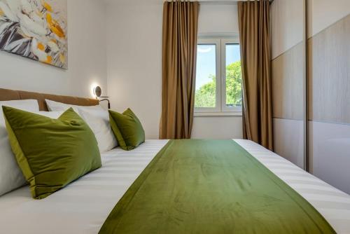 a bedroom with a large bed with green pillows at Villa Kate ZadarVillas in Knežević