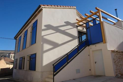um edifício branco com janelas azuis e uma porta em EL BAILE, casa con jacuzzi al lado de Peñafiel em Olmos de Peñafiel