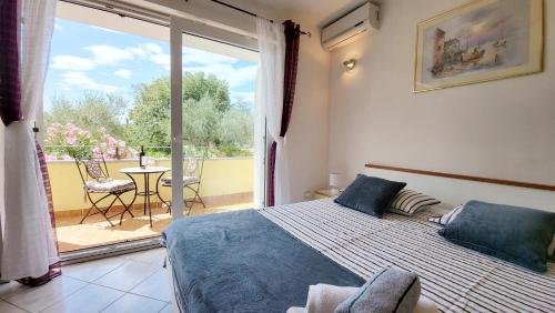 ein Schlafzimmer mit Bett und Blick auf einen Balkon in der Unterkunft Apartmani Agava in Čižići