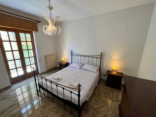 a bedroom with a bed with two night stands and a chandelier at Appartamento vista Isole Eolie in Acquedolci