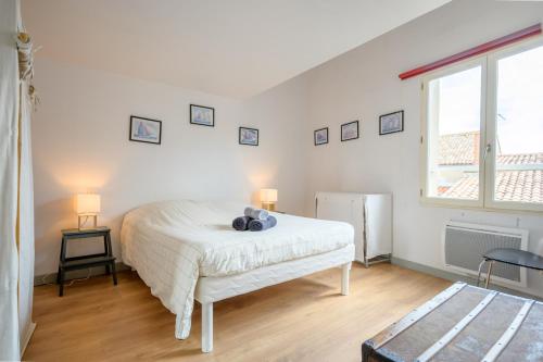 una camera con un letto bianco e una finestra di Appart le Grignon a Saint-Martin-de-Ré