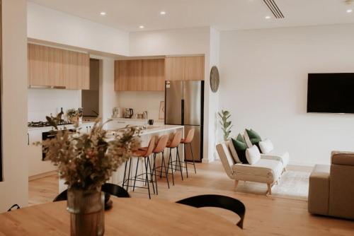eine Küche und ein Wohnzimmer mit einem Tisch und Stühlen in der Unterkunft SYLO Luxury Apartments - LVL 2 in Adelaide