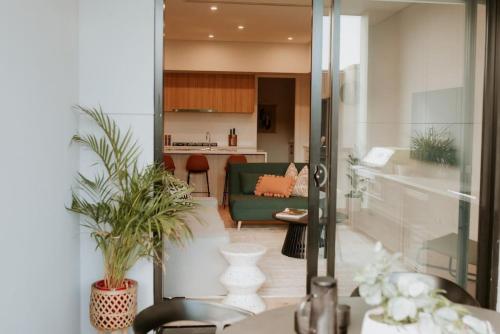 a living room with a green couch and a kitchen at SYLO Luxury Apartments - LVL 2 in Adelaide