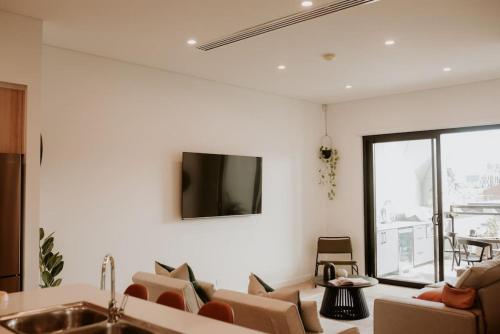 - un salon avec des canapés et une télévision murale dans l'établissement SYLO Luxury Apartments - Penthouse LVL 3, à Adélaïde