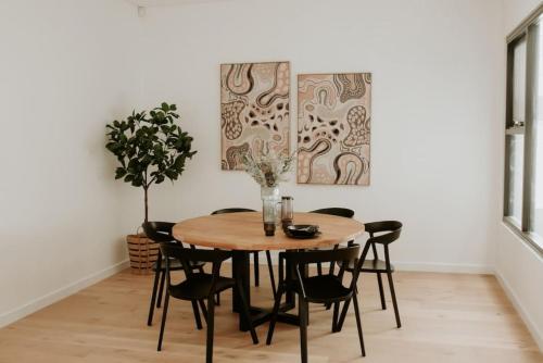 a dining room with a wooden table and black chairs at SYLO Luxury Apartments - Penthouse LVL 3 in Adelaide