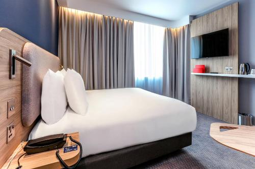 a hotel room with a large bed and a tv at Holiday Inn Express - Hamburg South A7-AS42 by IHG in Egestorf