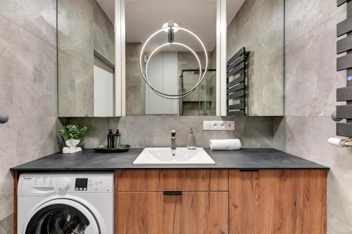 a bathroom with a washing machine and a sink at Downtown Apartments DOKI Living & Foodhall in Gdańsk