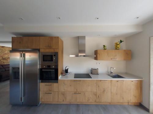 a kitchen with wooden cabinets and a stainless steel refrigerator at Casa Rojo in Camariñas