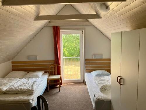 a attic room with two beds and a window at Gammelgaard Feriecenter in Læsø