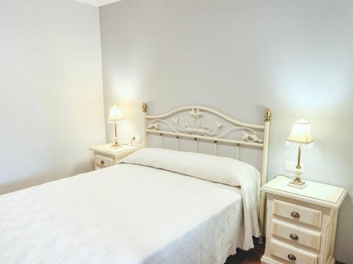 1 dormitorio con 1 cama blanca y 2 mesitas de noche en CASA CASTAÑEIRA, en Combarro