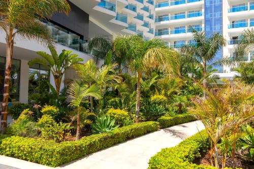 a garden in front of a building with palm trees at NissiBlu Beach Resort in Ayia Napa