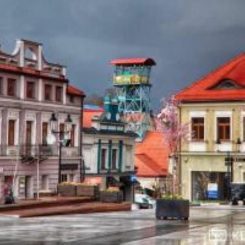 a group of buildings with a tower in the background at Klimatyczny apartament przy bocheńskim Rynku. in Bochnia