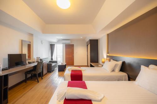 a hotel room with two beds and a desk at Golden Jade Suvarnabhumi in Lat Krabang