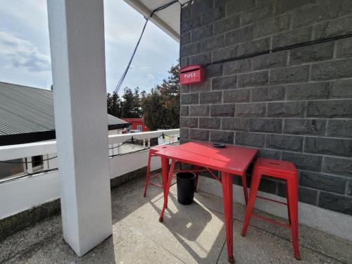 einem roten Tisch und zwei Hocker neben einer Ziegelwand in der Unterkunft Jeju Mermuri in Seogwipo