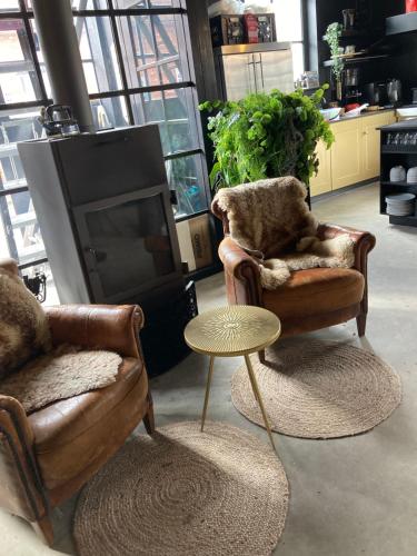 a living room with two chairs and a table and a tv at Logerij De Schuur in Zierikzee