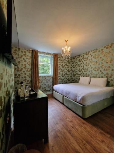 a bedroom with a bed and a chandelier at RainHill Hall Hotel in Rainhull