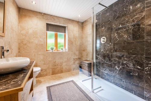 a bathroom with a glass shower and a sink at Millwood in Horstead