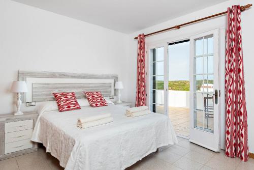 sypialnia z łóżkiem z czerwonymi poduszkami w obiekcie Villa Cala Llonga w mieście Mahón