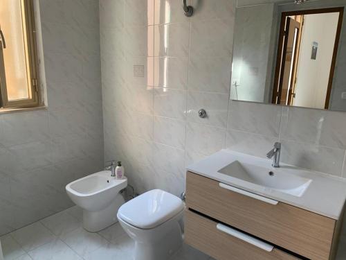 La salle de bains blanche est pourvue de toilettes et d'un lavabo. dans l'établissement Le Saline, à Margherita di Savoia