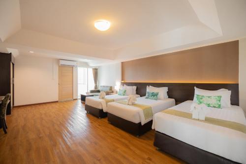 a hotel room with two beds and a couch at Golden Jade Suvarnabhumi in Lat Krabang