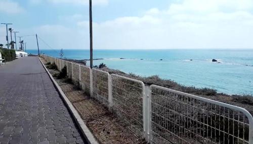 a fence on the side of a road next to the ocean at חופים מול הים in Bat Yam