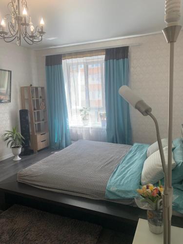 um quarto com uma cama com cortinas azuis e um candeeiro em Квартал em Khmelʼnytsʼkyy