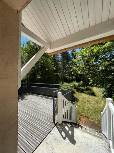 un porche d'une maison avec une terrasse avec des arbres dans l'établissement Gîte Maison Fougères droite Saint-Préjet d'Allier 14 personnes, à Saint-Préjet-dʼAllier