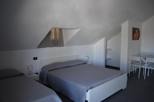 a white bedroom with two beds and a window at Villa Le Ninfee in Menfi