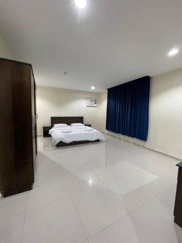 um quarto com uma cama e uma cortina azul em قصر الجادل للشقق الفندقية em Ahad Rafidah