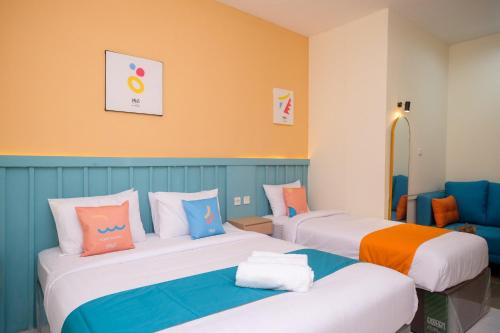 two beds in a room with orange and blue at Sans Hotel City Inn Solo by RedDoorz in Solo