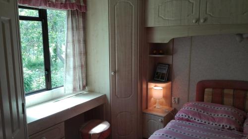 een slaapkamer met een bed en een raam bij Mobilhome Camping Paradijs in Zlatá Koruna