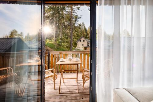 a screened porch with a table and chairs on a deck at TRI VODY Demänovská Dolina in Liptovský Mikuláš