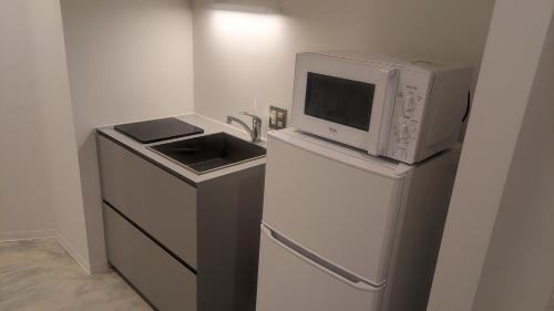 a microwave sitting on top of a refrigerator with a sink at Mont-モン-KAMOGAWA STAY and HOTEL in Kyoto