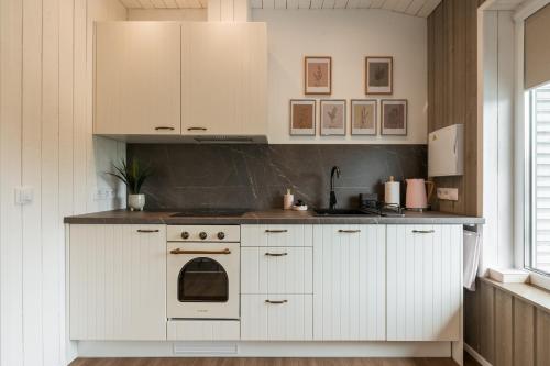 a kitchen with white cabinets and a stove at Lapmanni Studios in Haapsalu