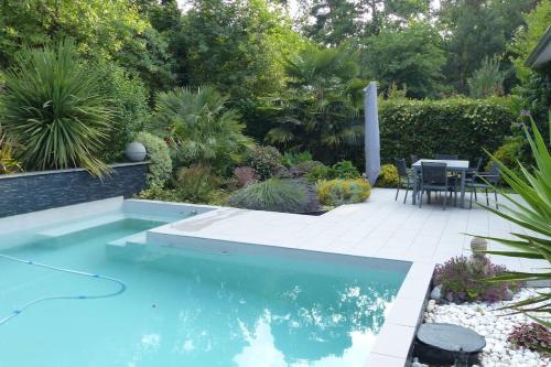 uma piscina no meio de um jardim em Villa d’archi. piscine privée en écrin de verdure em Mérignac