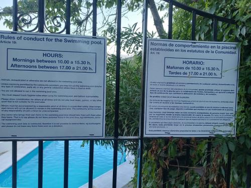 two signs on a fence next to a swimming pool at El Nogal in Bubión