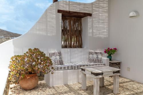 a patio with a bench and a table and a window at Calma Beach House in Elia Beach
