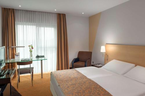 um quarto de hotel com uma cama e uma secretária em Dorint An der Messe Köln em Colônia