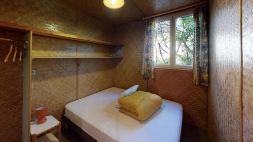 une petite pièce avec un lit et une fenêtre dans l'établissement Chalet des Lucioles, à Montréal