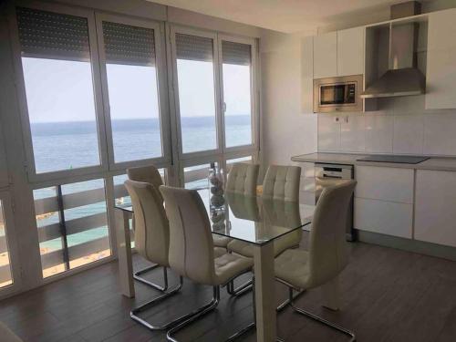 a kitchen with a glass table and chairs and the ocean at PRIMERA LÍNEA DE PLAYA, LA ARENA A TUS PIES in Aguadulce