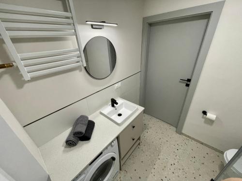 La salle de bains blanche est pourvue d'un lavabo et d'un miroir. dans l'établissement Apartament w Śródmieściu, à Gdynia