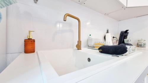 - une cuisine blanche avec un évier et un robinet dans l'établissement Le Stan - Centre - Parking - Extérieur - Fibre - Relax BNB, à Colmar