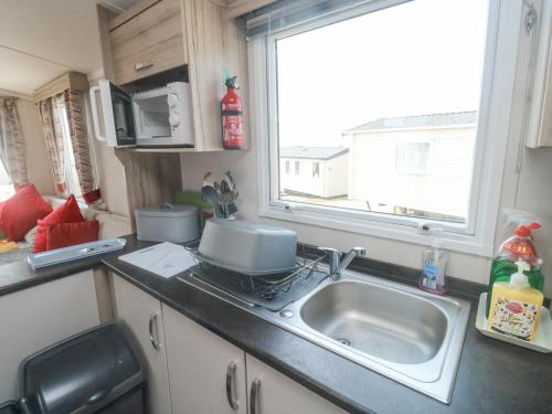 una piccola cucina con lavandino e finestra di Goodison Devon Cliff a Exmouth